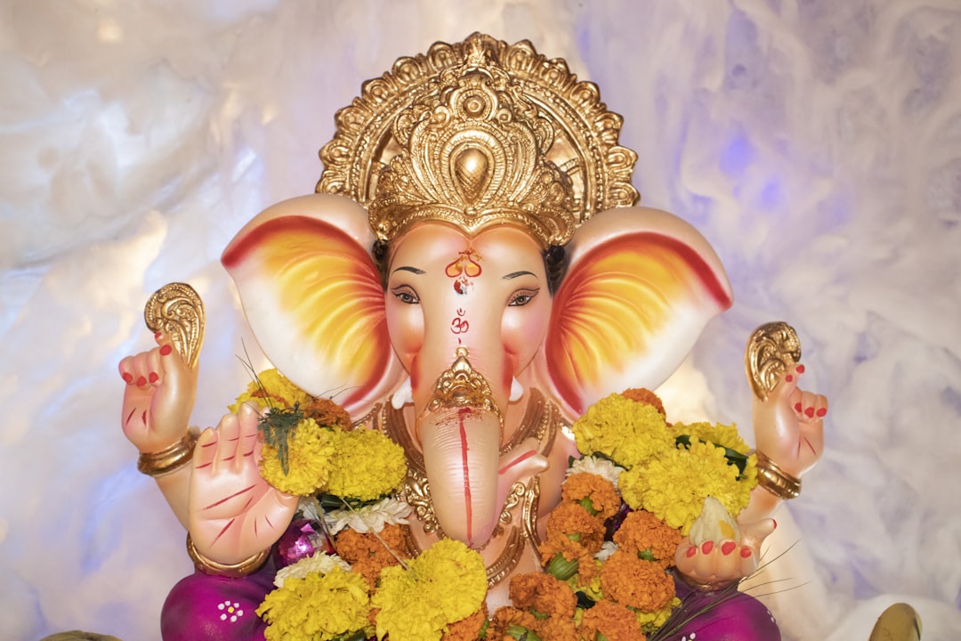 gold hindu deity figurine on pink textile,