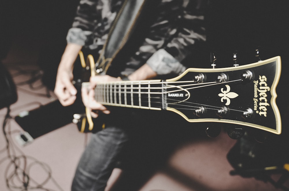 person playing electric guitar in black and white long sleeve shirt