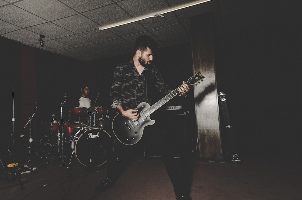 man in black and white plaid dress shirt playing electric guitar