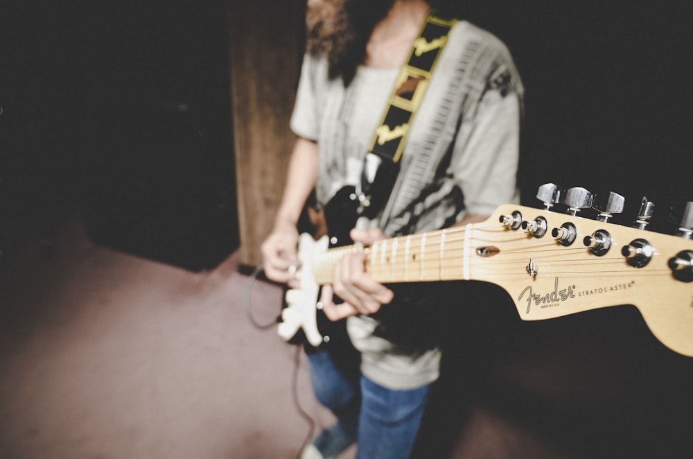 man in white shirt playing electric guitar