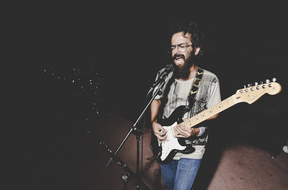 man in black and white jacket playing electric guitar