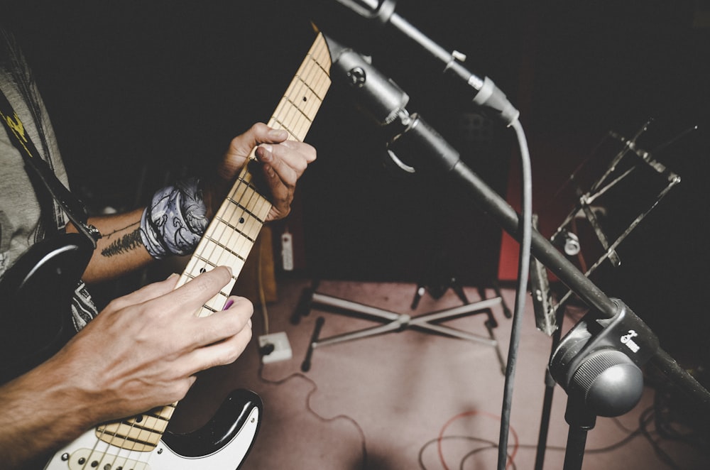 person playing brown and white electric guitar