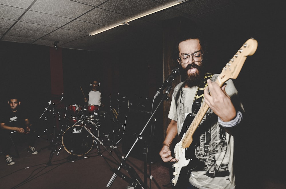 man in black and white crew neck t-shirt playing electric guitar