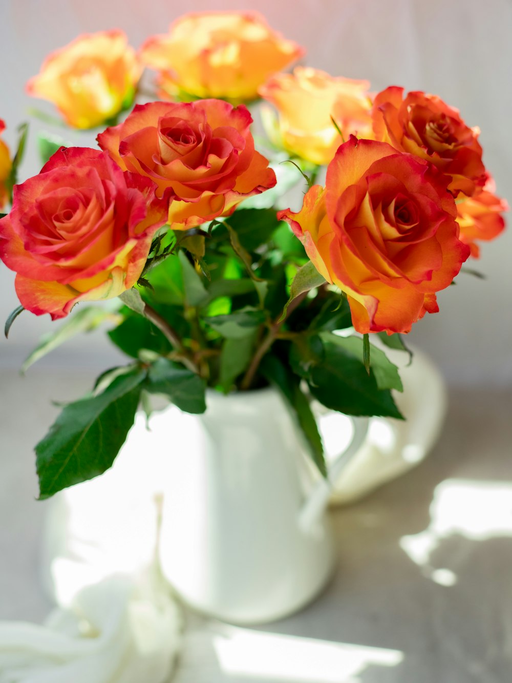 Roses rouges et jaunes dans un vase en céramique blanche