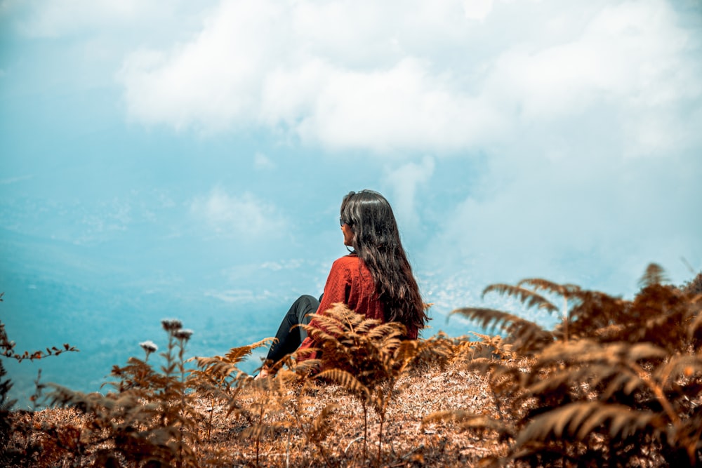 woman in black long sleeve shirt sitting on brown dried leaves during daytime