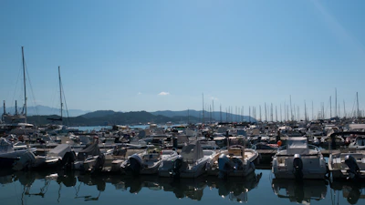 A spacious motorboat docked at a bustling marina with mountains in the background.