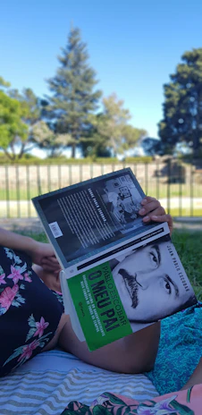A smiling woman reading a 'Mudança de Vida' guide in a peaceful park setting