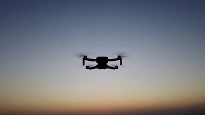 A sleek hybrid VTOL drone taking off from a rooftop drone hub at sunrise.