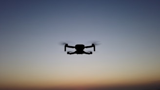 A sleek logistics drone lifting off from a warehouse rooftop at dawn, city skyline in the background.