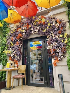 An elegant umbrella stand made of wrought iron, placed beside a vintage-style entryway bench with plush cushions.