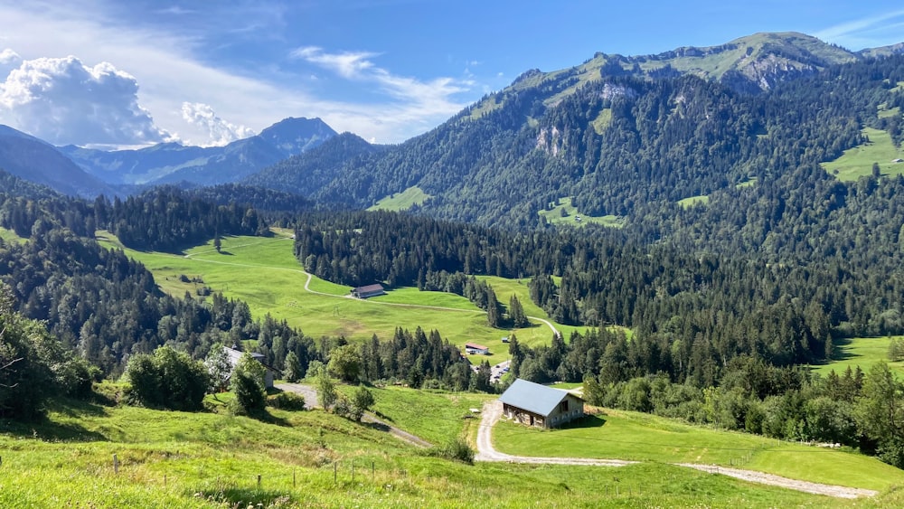 green grass field near green mountains under blue sky during daytime