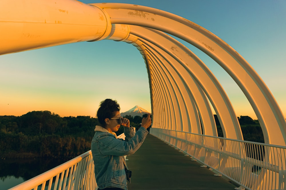 man in gray jacket standing on bridge during daytime