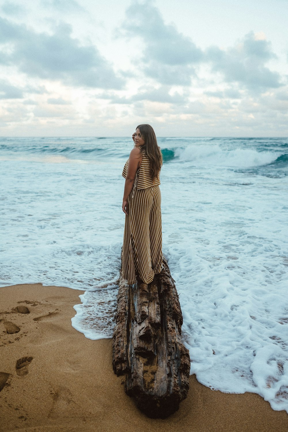 woman in brown and white stripe dress standing on beach during daytime