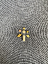 A collection of various shaped pills and tablets is arranged on a woven, textured surface with a circular pattern.