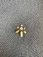A collection of various shaped pills and tablets is arranged on a woven, textured surface with a circular pattern.