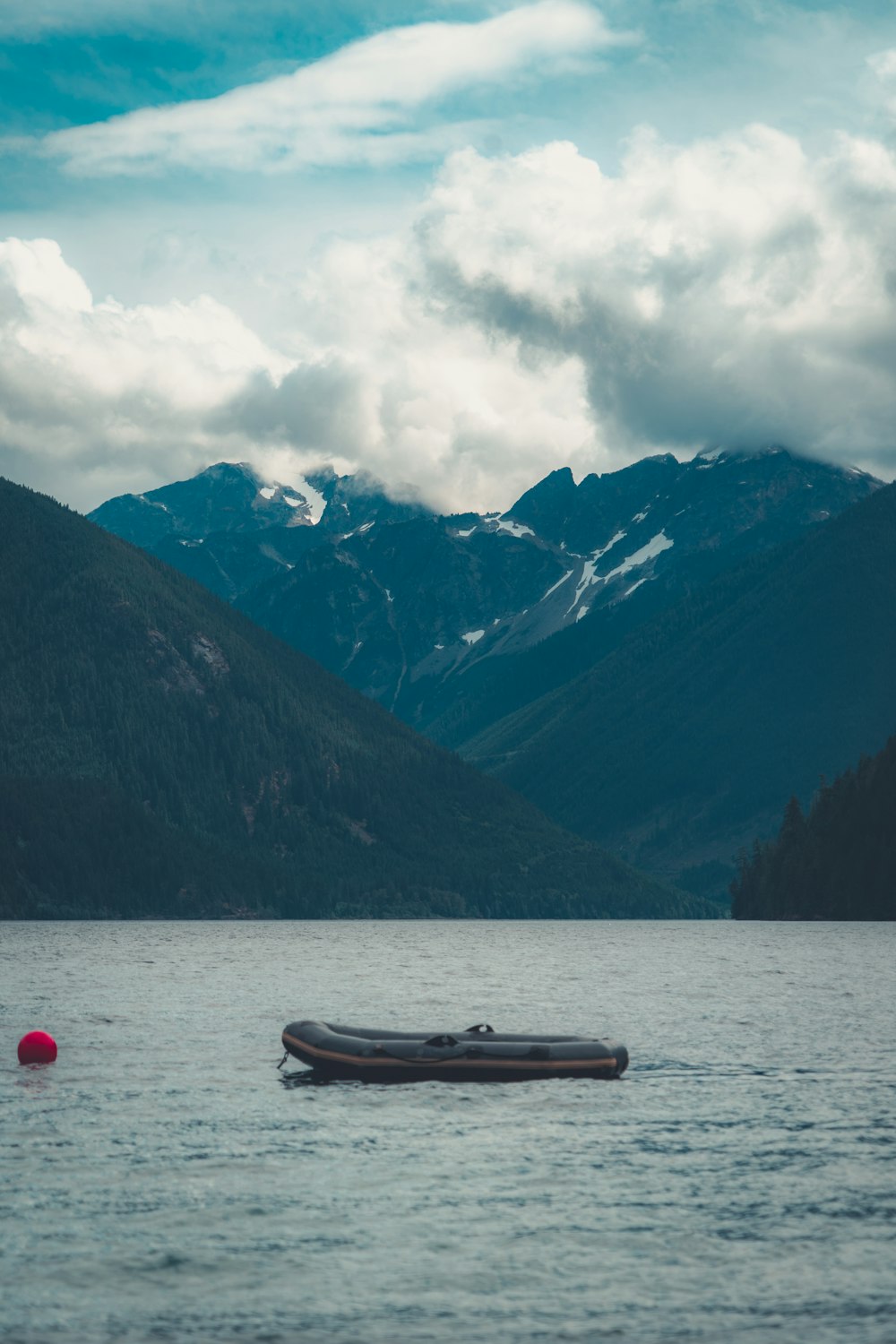 white and red kayak on lake near mountains under white clouds and blue sky during daytime