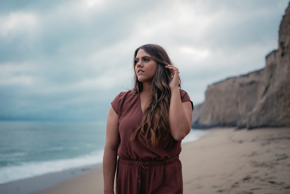 woman in red dress standing on beach during daytime