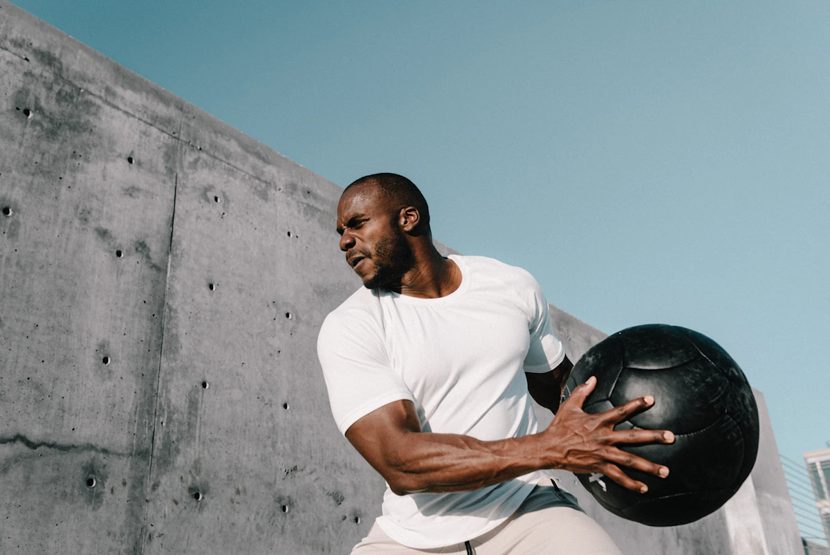 An athlete training outdoors with a weighted medicine ball