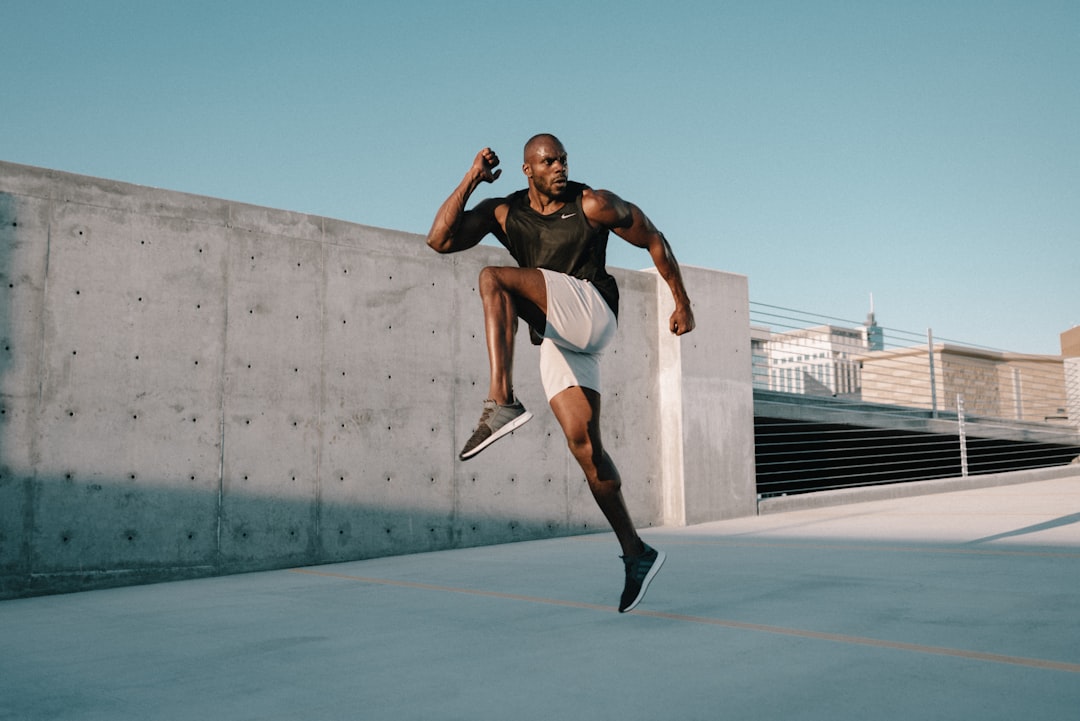 man in black tank top and white shorts jumping on mid air during daytime