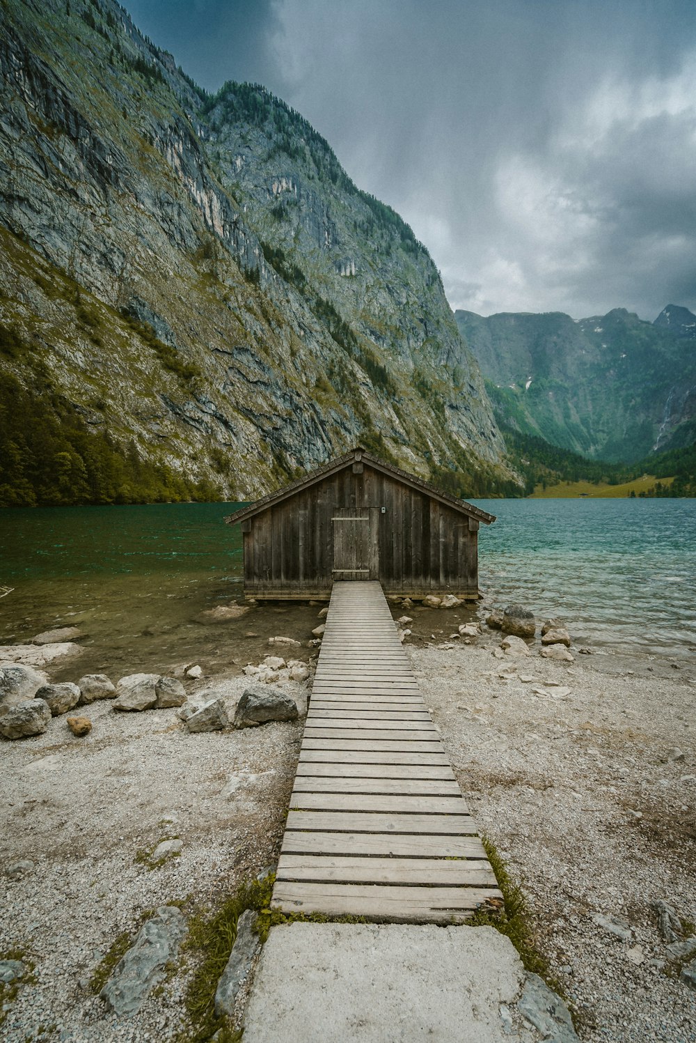 brown wooden house on rocky shore near mountain during daytime