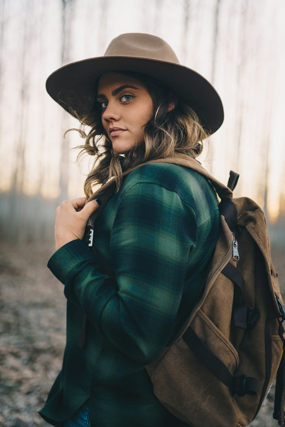 Femme en chemise à manches longues à carreaux vert et noir portant un chapeau noir