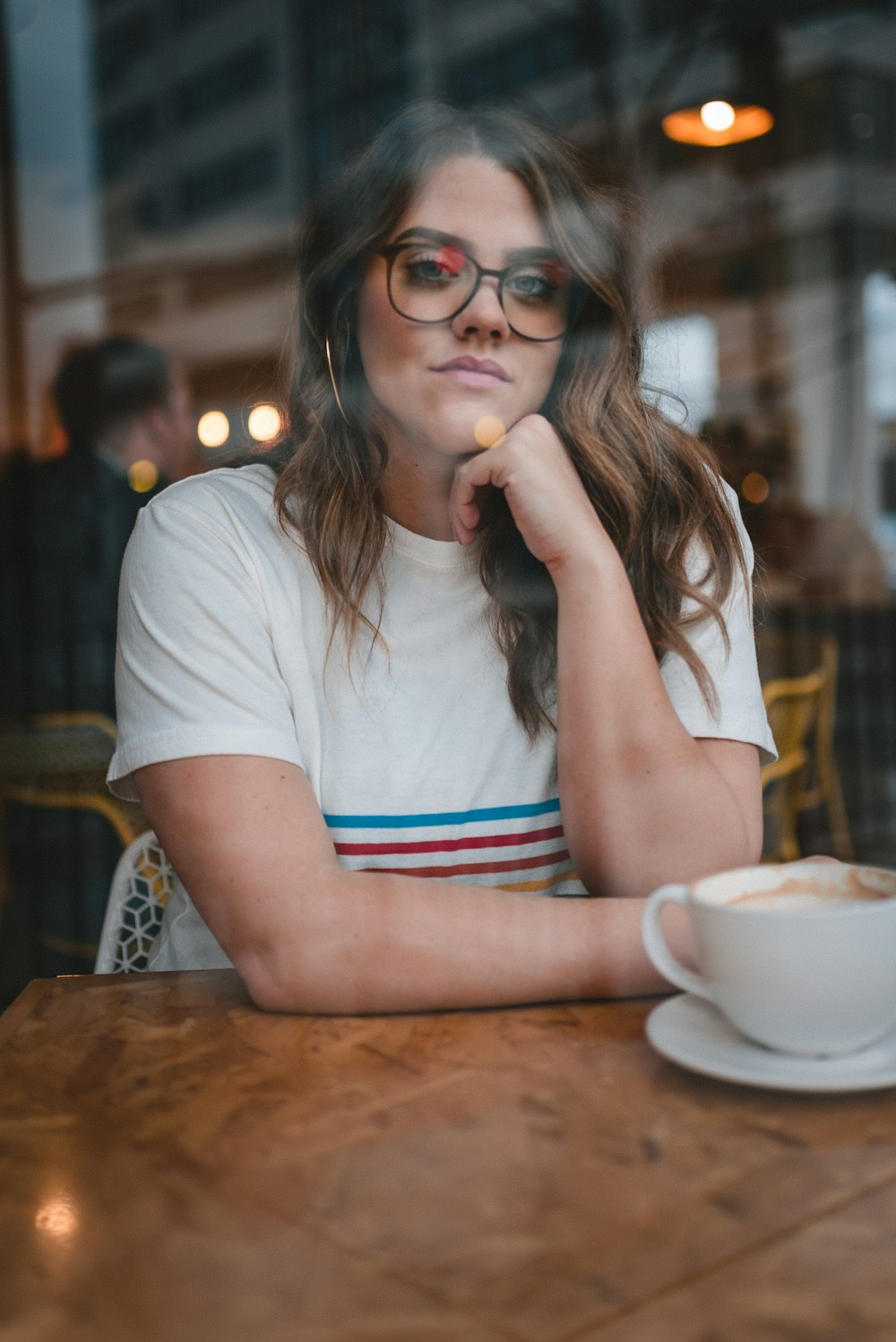 woman in white crew neck t-shirt wearing black framed eyeglasses sitting at the table