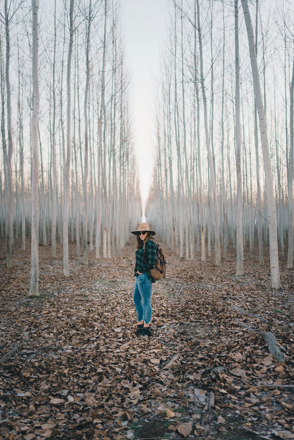 man in brown jacket standing on brown dried leaves during daytime