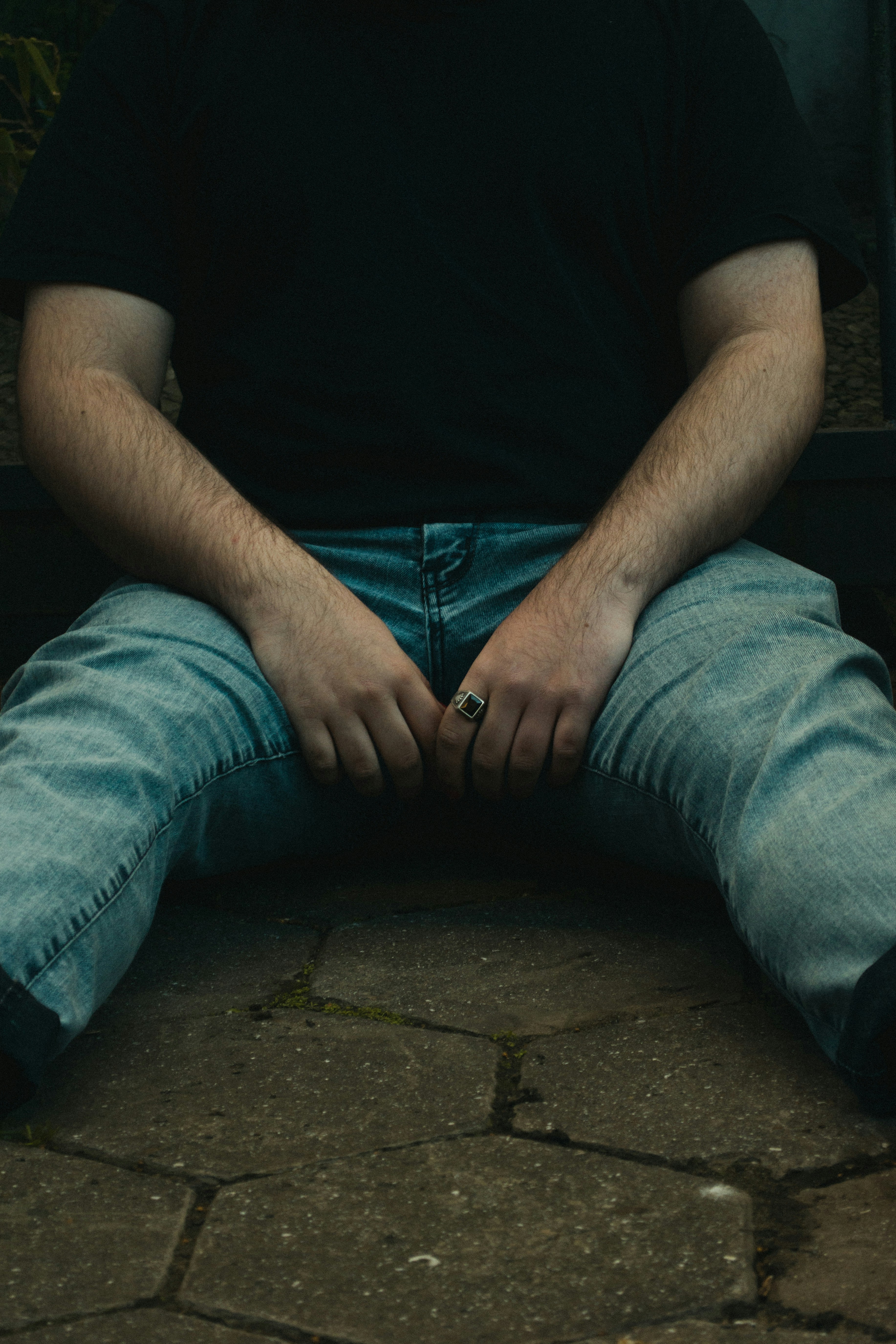 orang dengan kemeja hitam dan jeans denim biru duduk di tangga beton