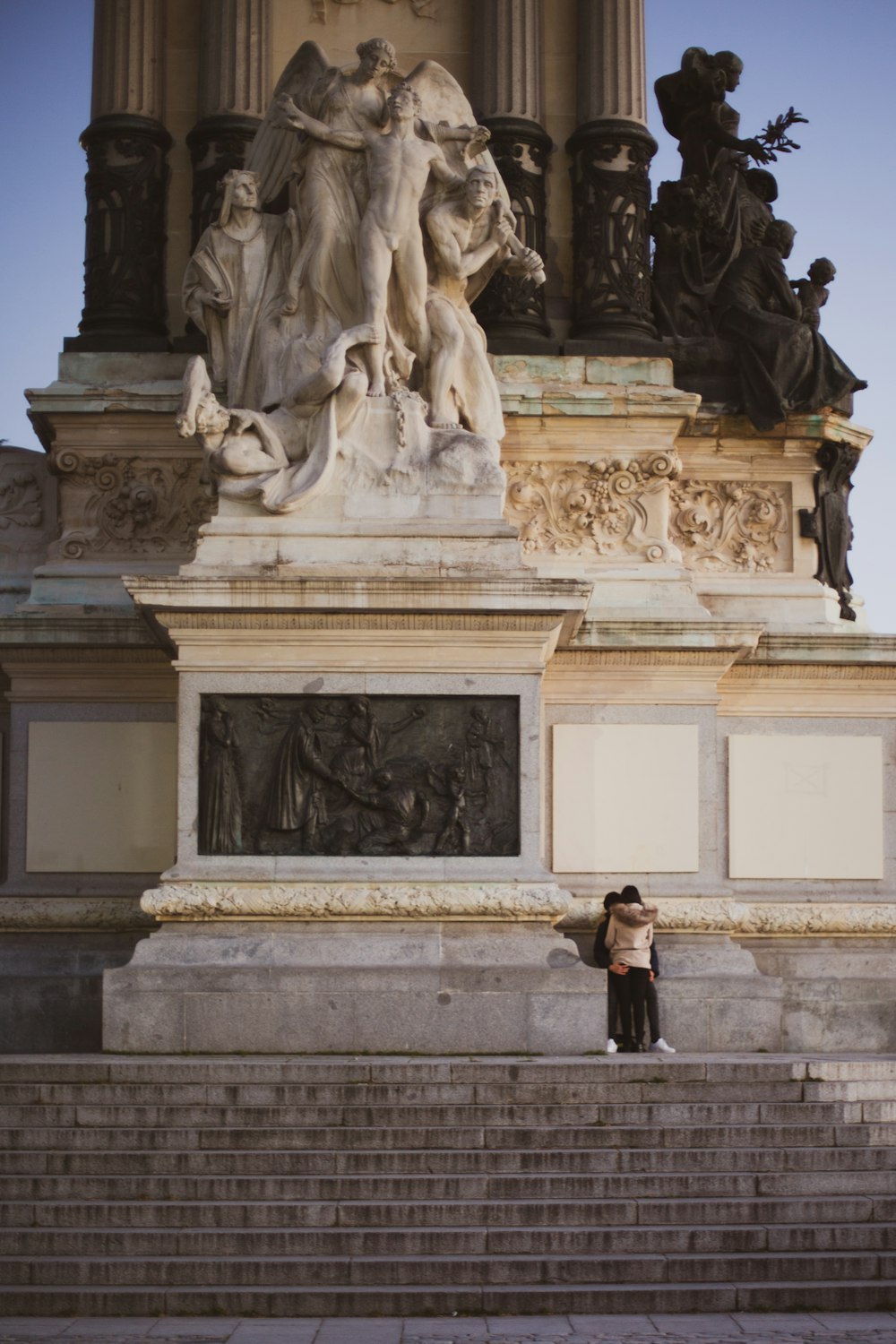Mujer en chaqueta negra de pie frente a la estatua