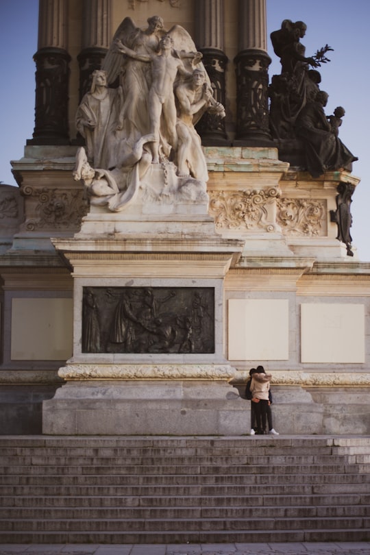woman in black jacket standing in front of statue in El Retiro Park Spain