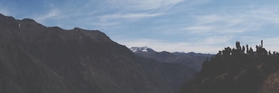 A panoramic mountain landscape with hikers enjoying the view under a clear blue sky.
