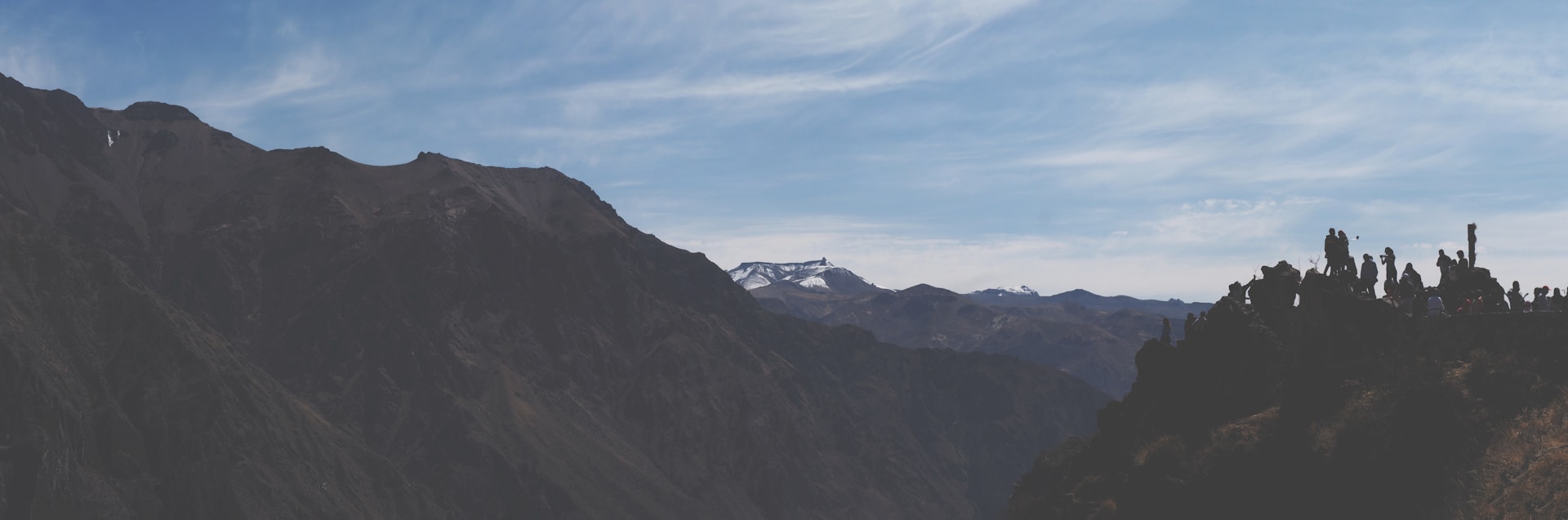 A panoramic mountain view with hikers pausing to take in the crisp air and endless horizons under a clear blue sky.