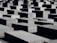 Numerous large concrete slabs are arranged in a grid-like pattern. The structures vary slightly in height, creating a visually striking geometric landscape. The shadows cast by the blocks add depth to the scene.
