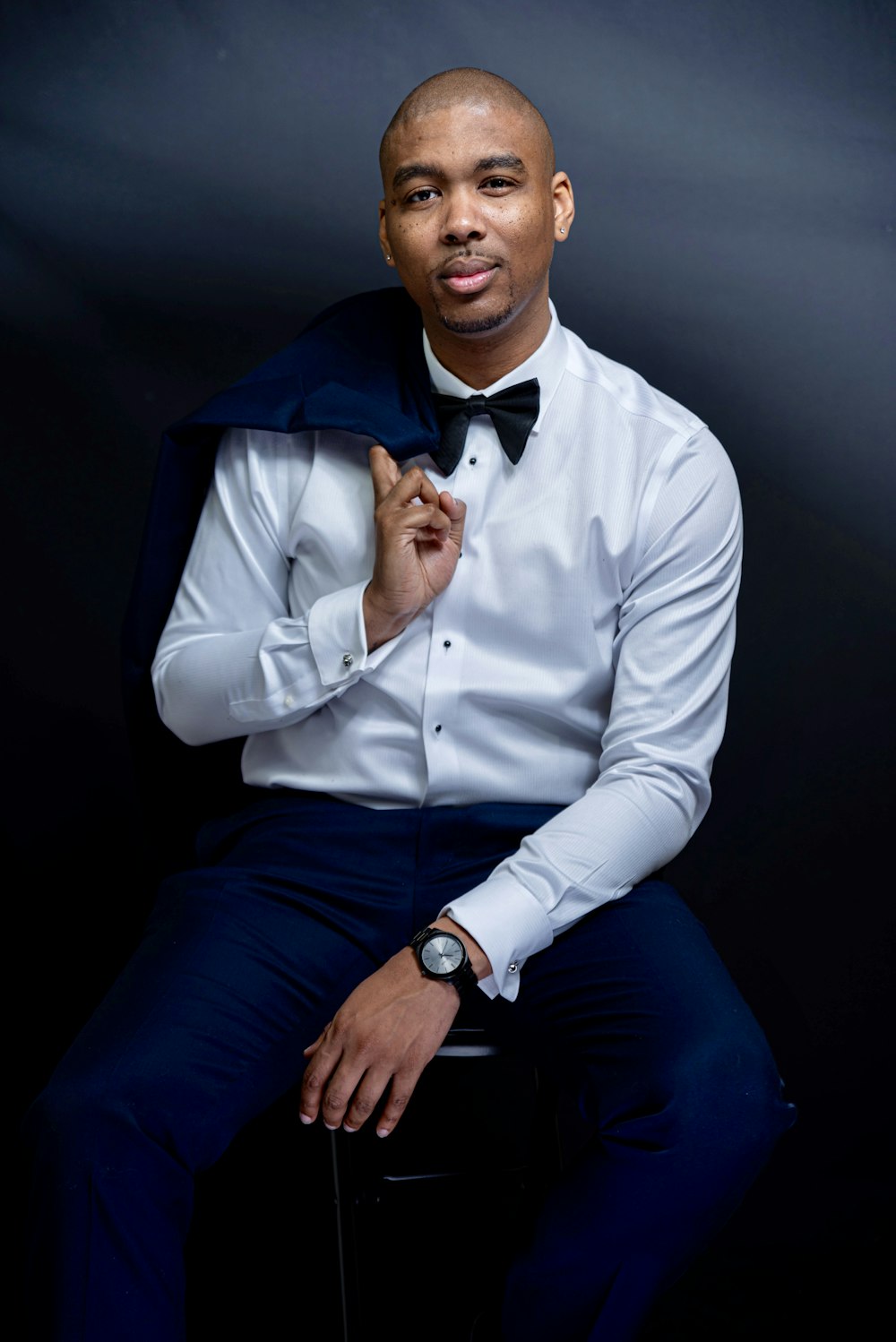 man in white dress shirt and blue pants sitting on black chair