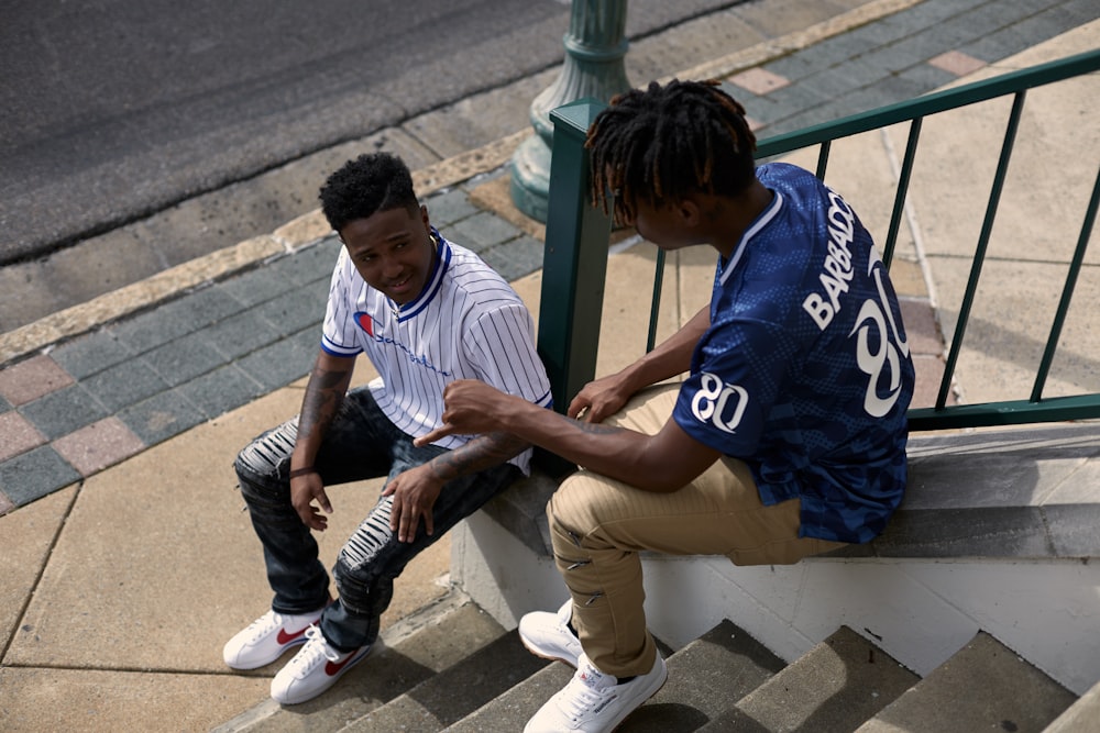 man in white and blue crew neck t-shirt sitting on concrete bench