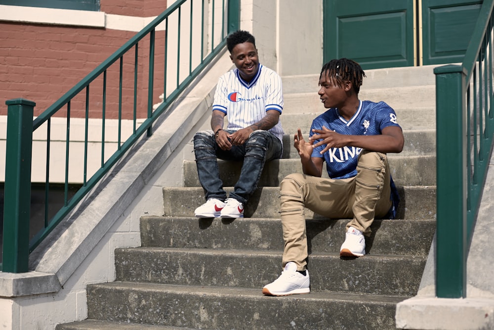 2 boys sitting on gray concrete stairs