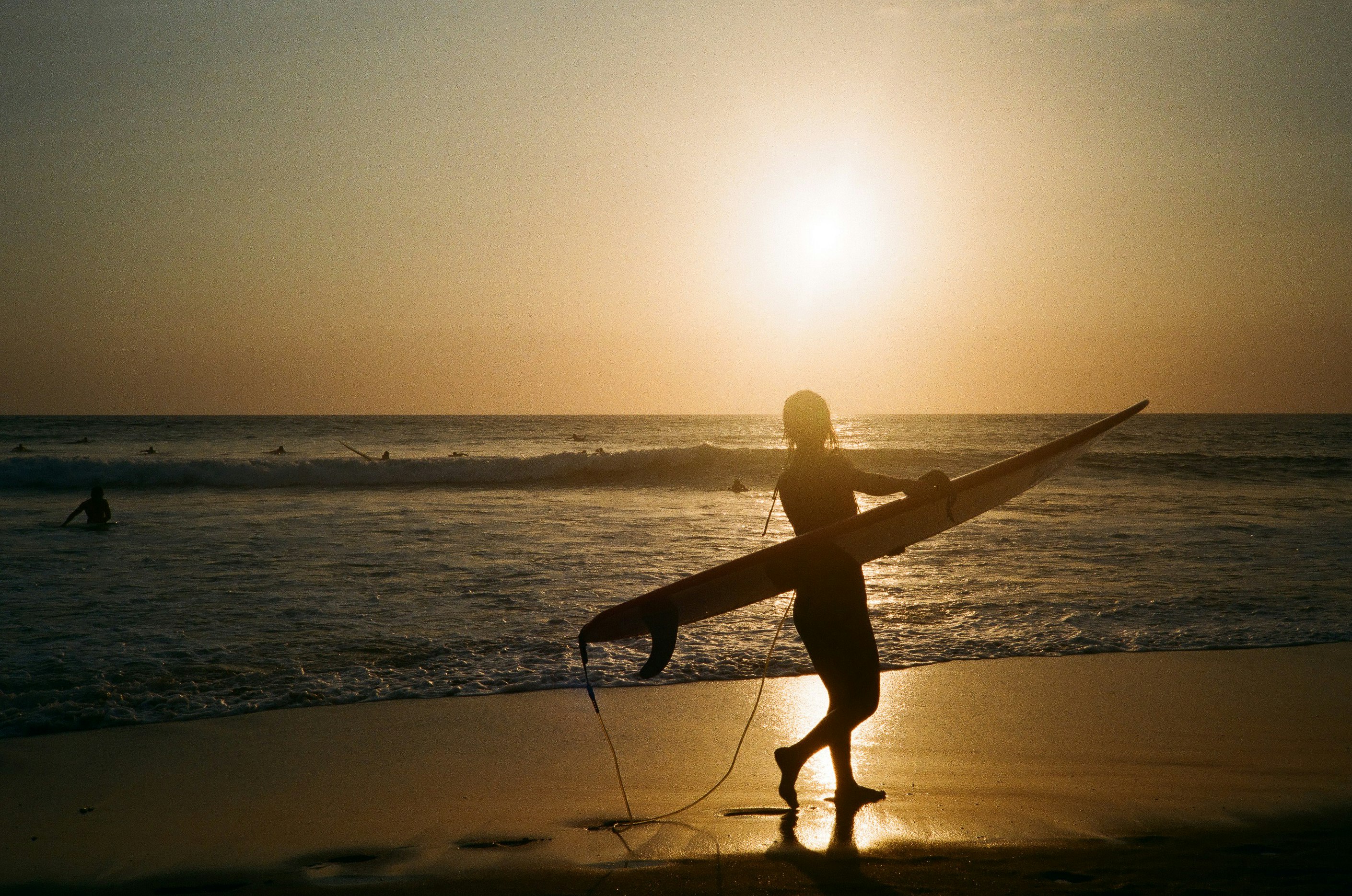 silhouette of man holding surfboard on beach during sunset
