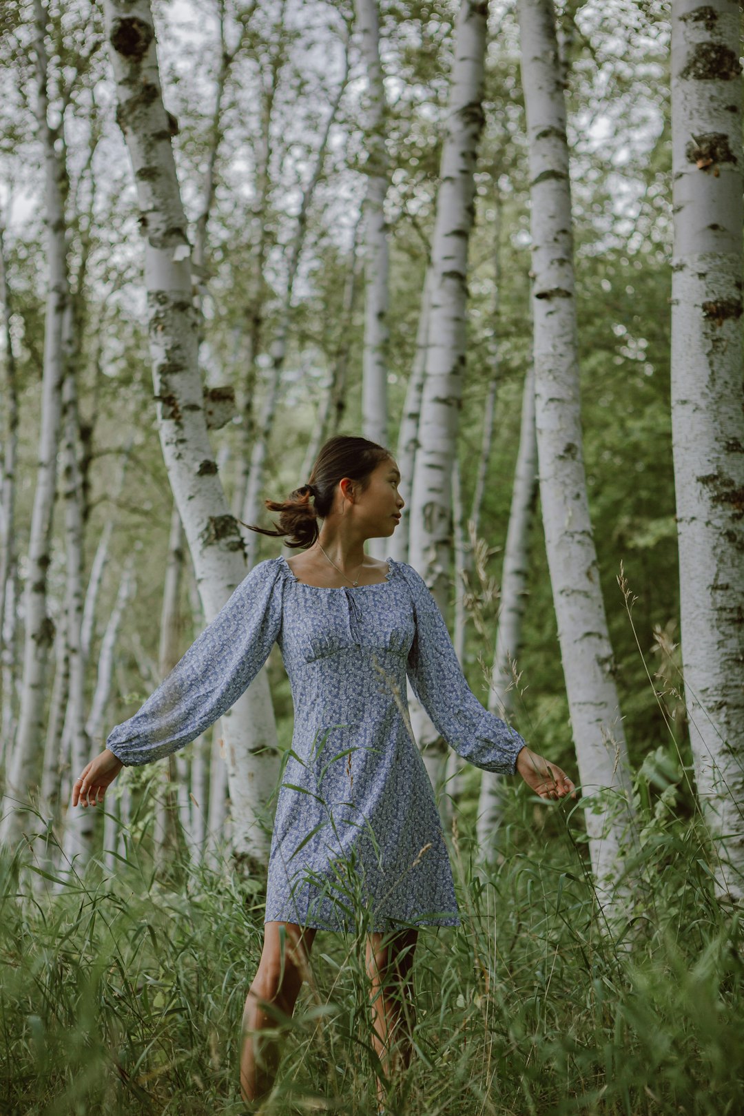 woman in blue long sleeve dress standing on forest during daytime
