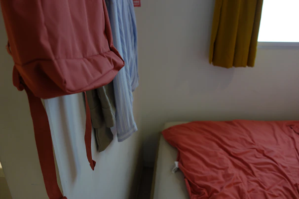 A cozy bedroom corner with a soft pastel laundry bag hanging on a wooden hook.