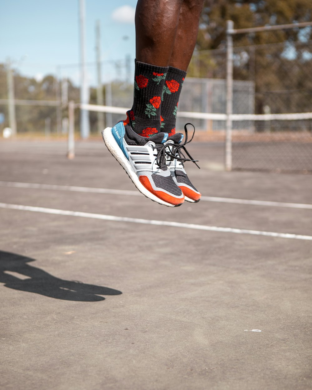 person in black and white nike air jordan 1 shoes running on track field during daytime