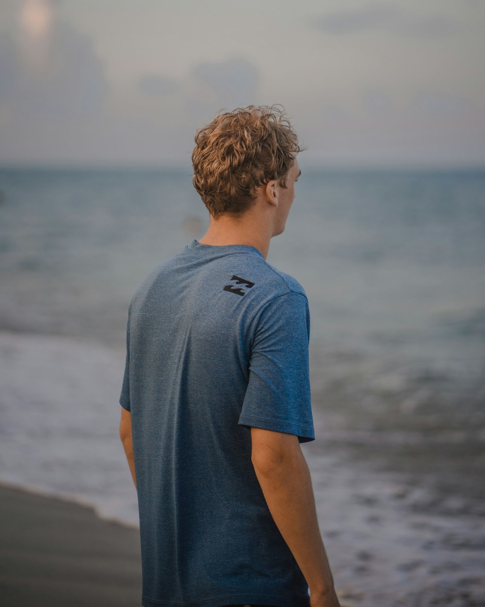 man in gray crew neck t-shirt standing on beach during daytime
