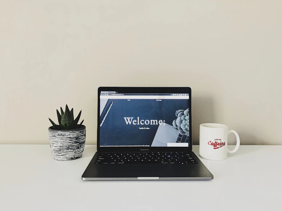 A friendly desk setup with a laptop, notebook, and a cup of coffee, inviting visitors to reach out.