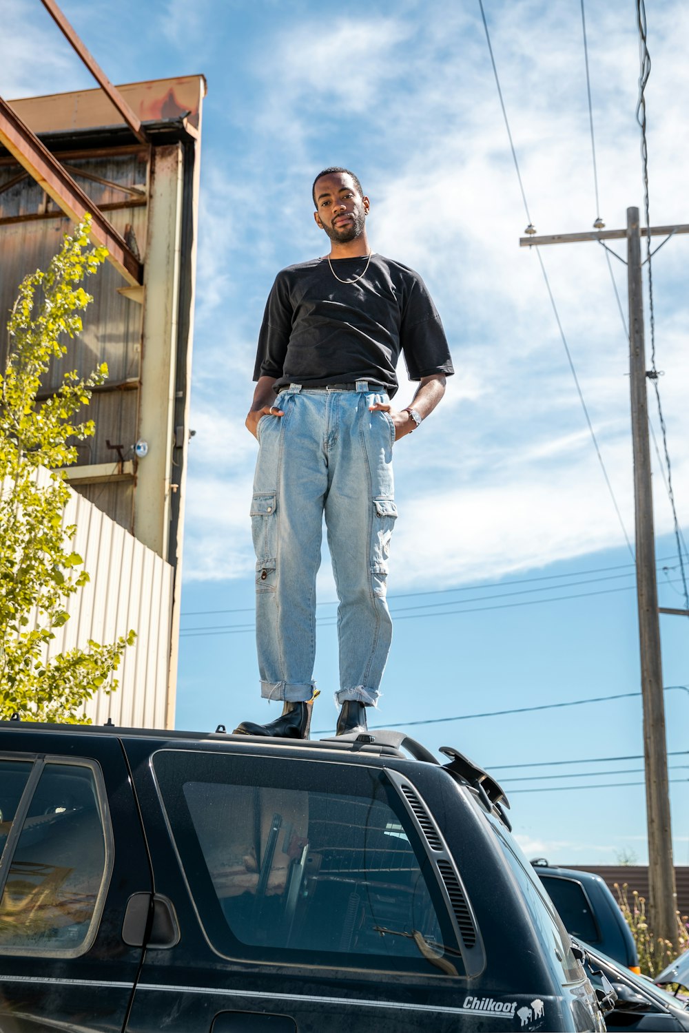 man in black crew neck t-shirt and blue denim jeans standing beside black car during