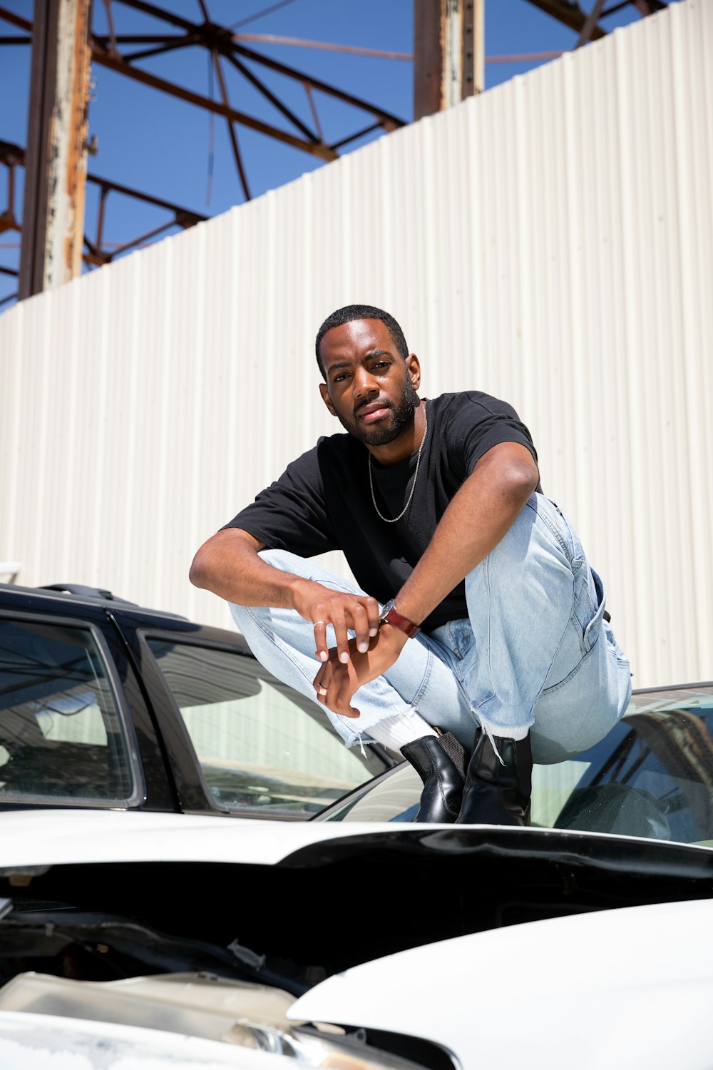 man in white button up t-shirt sitting on car