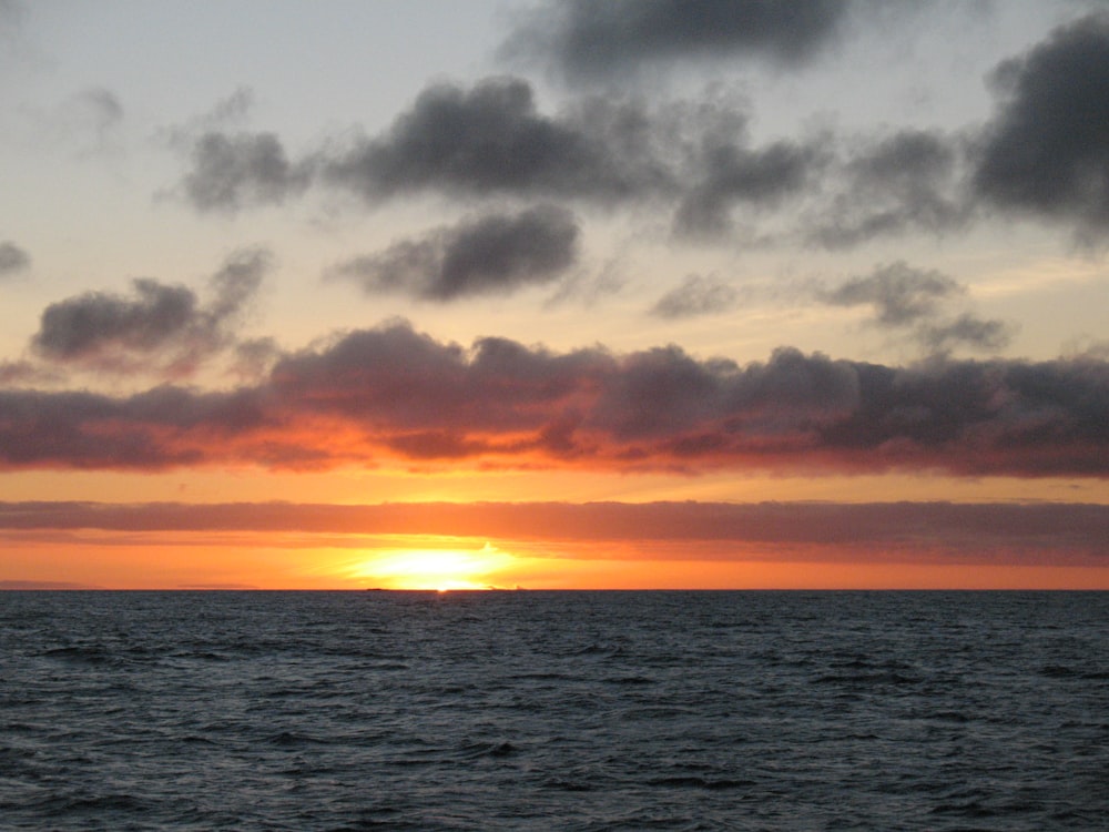 body of water under cloudy sky during sunset