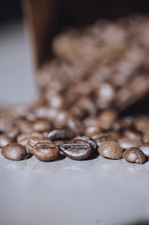 Detail of freshly roasted coffee beans resting on a rustic surface with soft shadows.