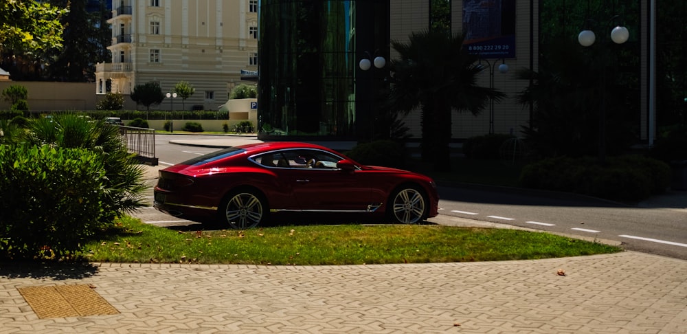 red coupe parked on sidewalk during daytime