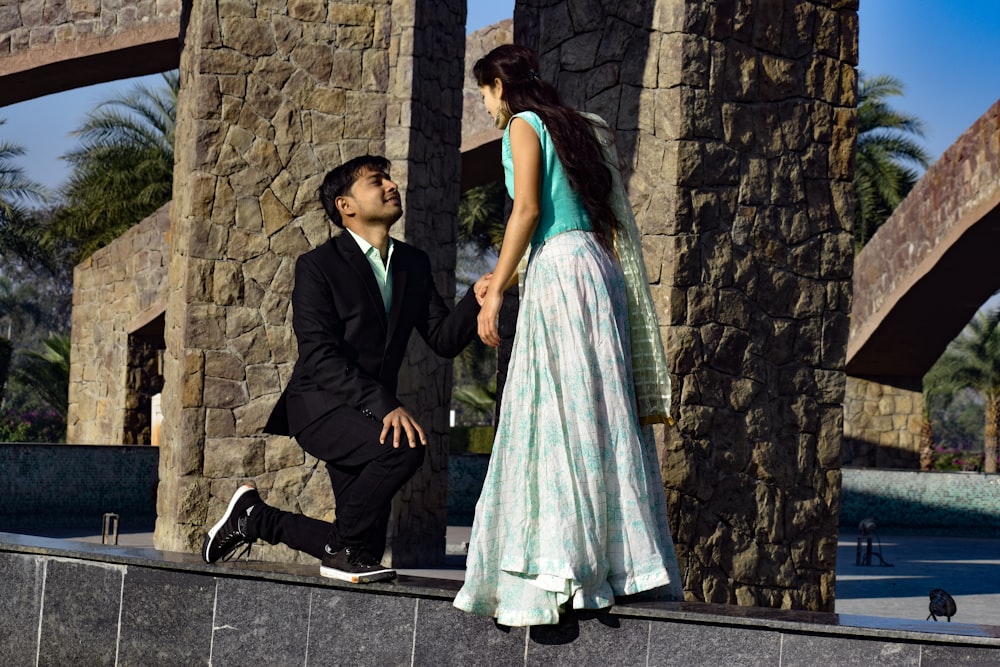 man in black suit jacket and woman in teal dress