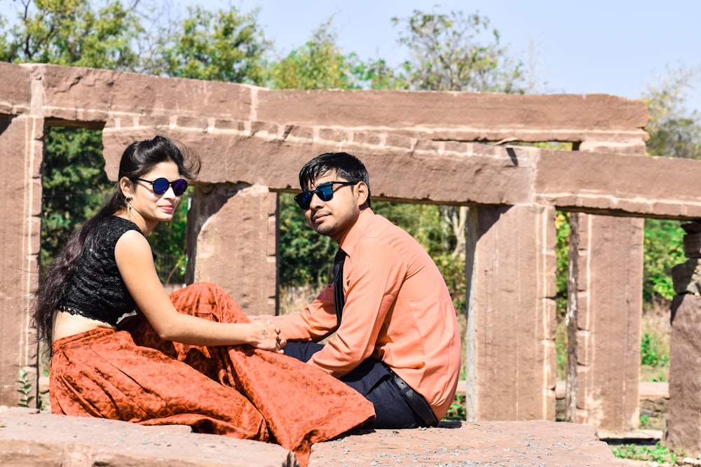 woman in orange dress sitting on concrete bench during daytime