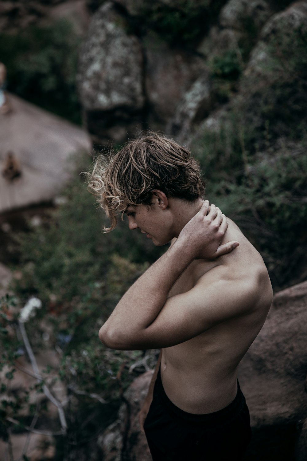 topless boy standing on brown dirt during daytime